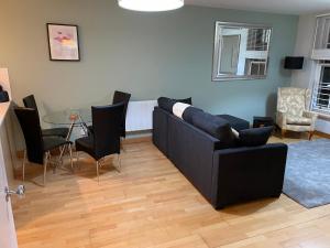 GREENWICH CENTRE NKY APARTMENT في لندن: غرفة معيشة مع أريكة سوداء وطاولة