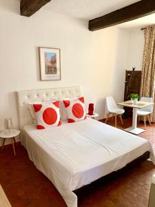 a bedroom with a bed with red and white pillows at le 1835, studio rouge-Corail in Moustiers-Sainte-Marie