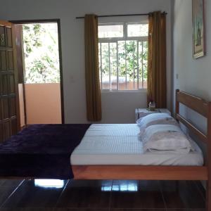 a bed in a room with two windows at Pousada Sossego da Vila - Trindade Paraty in Trindade