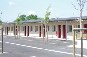un bâtiment avec des arbres dans un parking dans l'établissement Motel des Landes, à Bénesse-Maremne