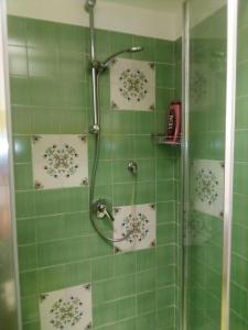 a bathroom with a shower with green tiled walls at Antico Casale Del Buono in Falconara Albanese