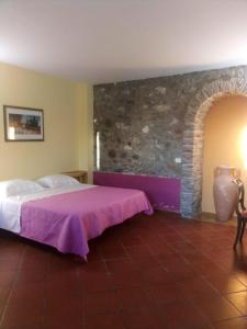 a bedroom with a bed and a stone wall at Antico Casale Del Buono in Falconara Albanese