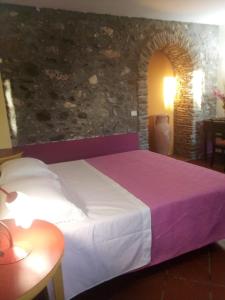 a bed in a room with a stone wall at Antico Casale Del Buono in Falconara Albanese