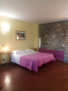 a bedroom with a bed with a purple blanket at Antico Casale Del Buono in Falconara Albanese
