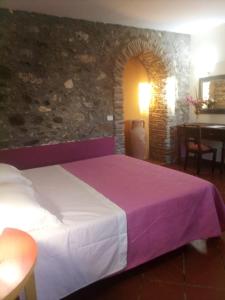 a bedroom with a large bed with a purple blanket at Antico Casale Del Buono in Falconara Albanese