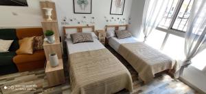 two beds in a living room with a couch at Huelintown in Málaga