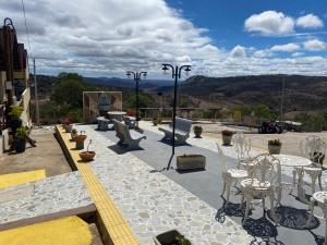een patio met stoelen en tafels en bergen op de achtergrond bij Encanto dos Pássaros in Monte das Gameleiras