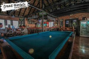 a pool table in front of a bar with people sitting at Great Hostels in Baños