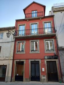 凡道Rustic House Fundão的一座红色的建筑,上面设有一个阳台