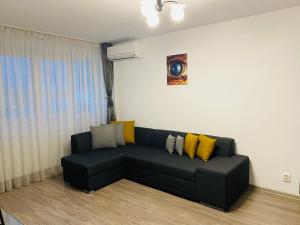 una sala de estar con un sofá negro con almohadas amarillas en Apartament Cristina, en Bucarest