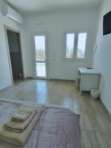 een grote witte kamer met een bed en een bureau bij Piccolo Ulivo B&B Salento in Vernole