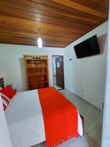 a bedroom with a red and white bed and a television at Pousada Canoa Caiçara Ilhabela in Ilhabela