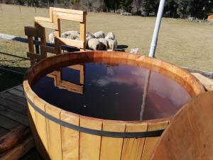 a barrel filled with water with sheep in a field at Cabañas Los Canelos Pucon, Hermosa Granja de 20 hectaréas a orillas del Río Liucura in Pucón