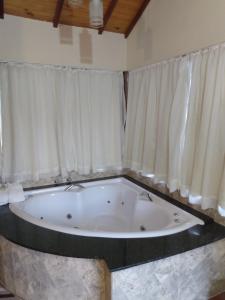 a large bath tub in a room with curtains at Chalés Recanto Vista do Valle in Monte Verde