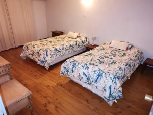 two beds in a room with wooden floors at Departamento acogedor en centro de San Fernando in San Fernando