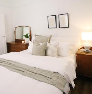 a bedroom with a white bed with pillows and a mirror at Waukivory Estate - The Cottage 
