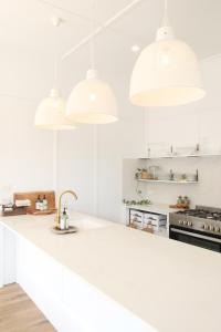 Waukivory Estate - The Cottage في Waukivory: مطبخ مع كاونترات بيضاء وثلاث أضواء قلادة