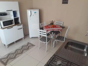 a kitchen with a table with chairs and a refrigerator at Apto Jockey 4 in Campos dos Goytacazes