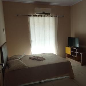 a bedroom with a bed with a window and a television at Apto Jockey 4 in Campos dos Goytacazes +7 photos