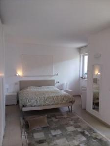 a white bedroom with a bed and a mirror at La Pervinca Apartments in Malcesine