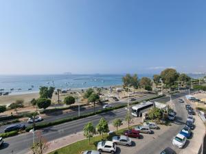uma movimentada rua da cidade com carros estacionados ao lado de uma praia em Super Modern Beachfront 1 bedroom - sleeps 4 em Limassol