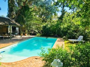 a swimming pool in a yard with a bench and trees at The Victorian of Church Street - Cape Dutch Quarters in Tulbagh