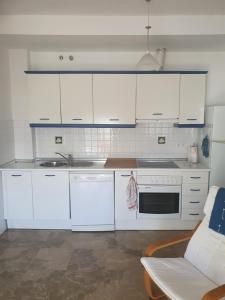 eine Küche mit weißen Schränken, einer Spüle und einer Couch in der Unterkunft Apartamento en Isla Cristina Puerto Deportivo in Isla Cristina