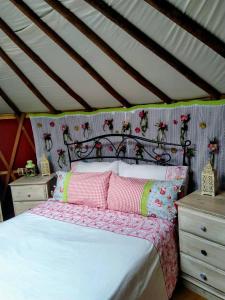 Santa Cruz do DouroにあるWoodpecker Yurtのベッドルーム1室(ピンクと緑の枕が付いたベッド1台付)
