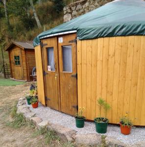 a wooden shed with potted plants in front of it at Woodpecker Yurt in Santa Cruz do Douro