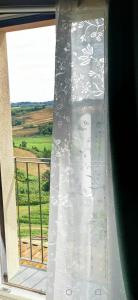 een gordijn op een raam met uitzicht op een veld bij La casa di Isola in Peccioli