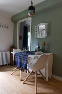 a dining room with a table and chairs and a mirror at La Maison de Dame Holda in Tanville