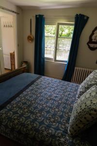 a bedroom with a blue bed and a window at La Maison de Dame Holda in Tanville