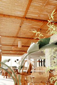 comedor con techos de madera y sillas de mimbre en Hotel Ionian, en Dhërmi