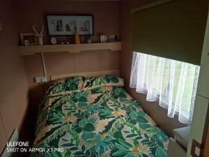 a small bedroom with a bed with a floral bedspread at Gina's Static caravan,118 Sandsgate in Hemsby