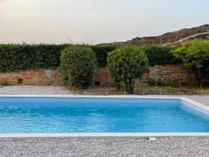 a blue swimming pool in front of a brick wall at Cape Sunset Villa in Makrotándalon