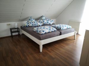 a bed with blue and white pillows on it at Familienfreundliche Ferienwohnung mit Wohlfühlbalkon und kostenlosem Parkplatz nahe Messe und Bodensee in Meckenbeuren