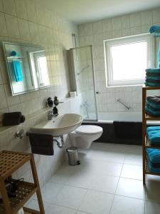 a bathroom with a sink and a toilet and a tub at Familienfreundliche Ferienwohnung mit Wohlfühlbalkon und kostenlosem Parkplatz nahe Messe und Bodensee in Meckenbeuren