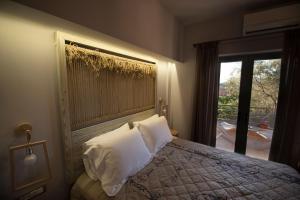 a bedroom with a bed with white pillows and a window at Kanathos Pigi in Nafplio