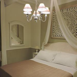 1 dormitorio con cama con dosel y lámpara de araña en Boutique Hotel Masolino, en Panicale