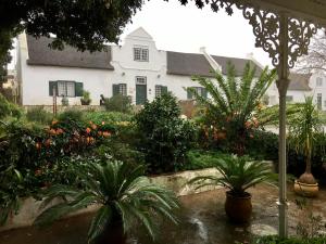 um jardim com plantas e uma casa branca em Tulbagh Country Guest House - Cape Dutch Quarters em Tulbagh