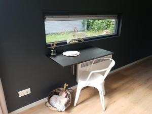 escritorio negro con silla blanca y ventana en Modern Tiny House op rustig Watersportpark, en Elahuizen