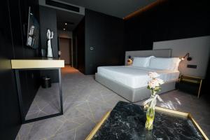 a bedroom with a bed and a table with flowers on it at The Central View Boutique Hotel in Vlorë