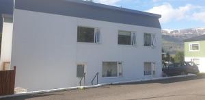 un edificio blanco con un coche aparcado delante de él en Apartment Tungata, en Seyðisfjörður