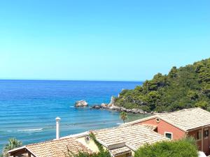 a beach with a pink house and the ocean at Corfu, Glyfada, Sea la vie apartment in Glyfada