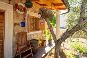 un porche de una casa con una silla y un árbol en Villa Flaveico, en Pašman