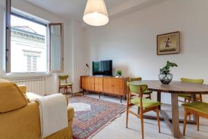 a living room with a table and a tv at Mamo Florence - Cavour Apartments in Florence
