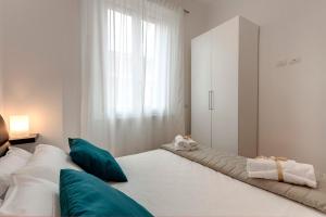 a white bedroom with a large bed with green pillows at Mamo Florence - Cavour Apartments in Florence