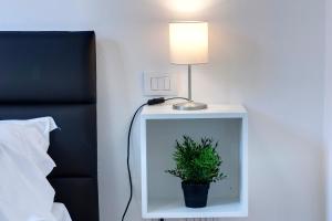 a lamp and a plant on a night stand next to a bed at Mamo Florence - Cavour Apartments in Florence