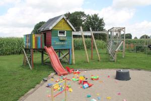 a playground with a house and a slide at Hof am Redder in Lindewitt