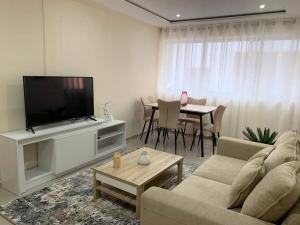 uma sala de estar com um sofá, uma televisão e uma mesa em kelly's House Plateau City Center em Praia